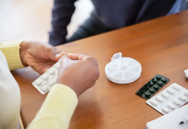 Hands arranging pills and medication containers on a table