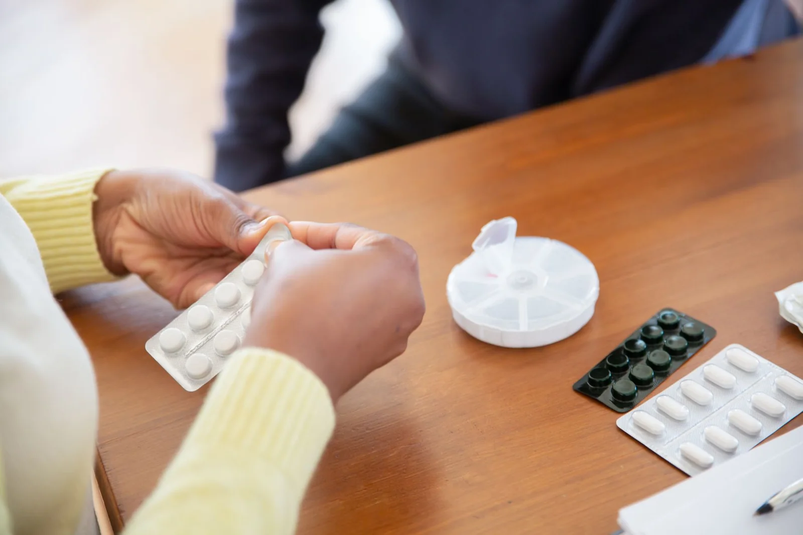 Hands arranging pills and medication containers on a table