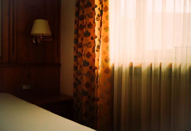 A bedroom with soft light through the curtains