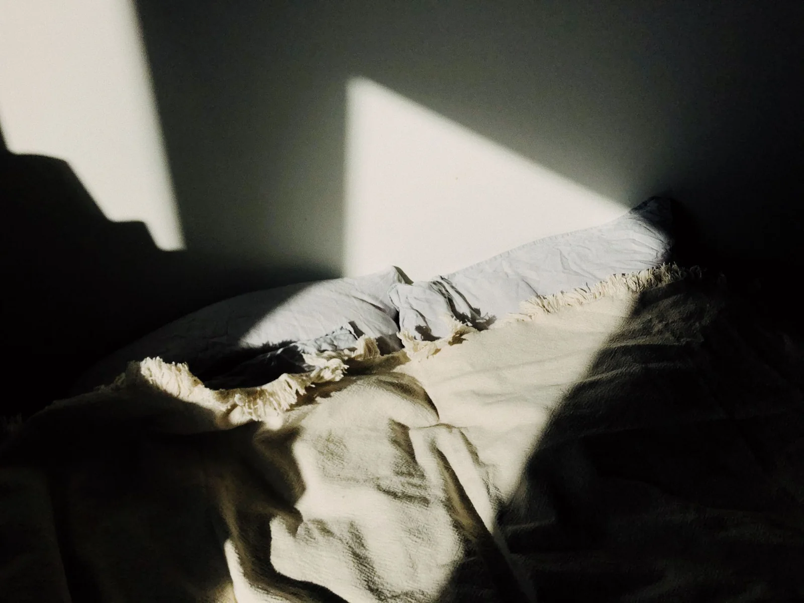 Sunlight falling across a bed and blanket
