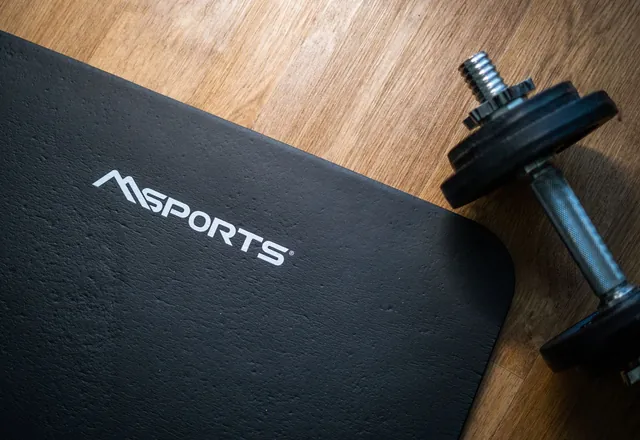 A dumbbell and exercise mat on a wooden floor