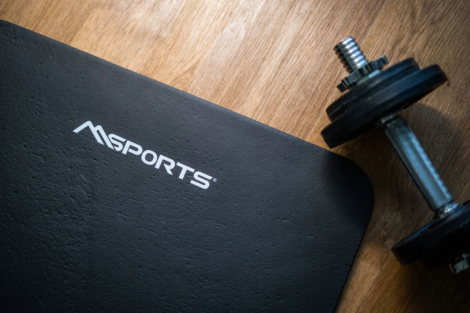 A dumbbell and exercise mat on a wooden floor