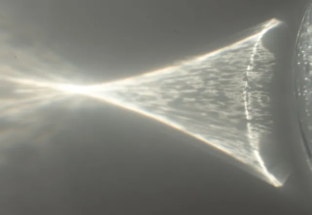 A glass of water casting a shadow on a white surface