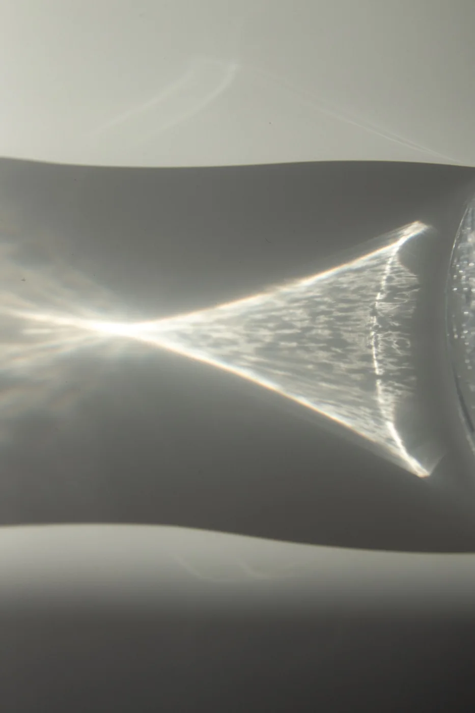 A glass of water casting a shadow on a white surface